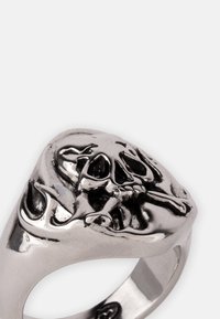 Sølv skalle ring med et detaljert design av skalle og krysning, satt på et hjerteformet ringbånd med en polert finish.