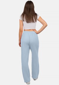 Lichtblauwe, wijde broek van textuurstof met een elastische tailleband. De achterkant toont een losse pasvorm en een casual ontwerp.