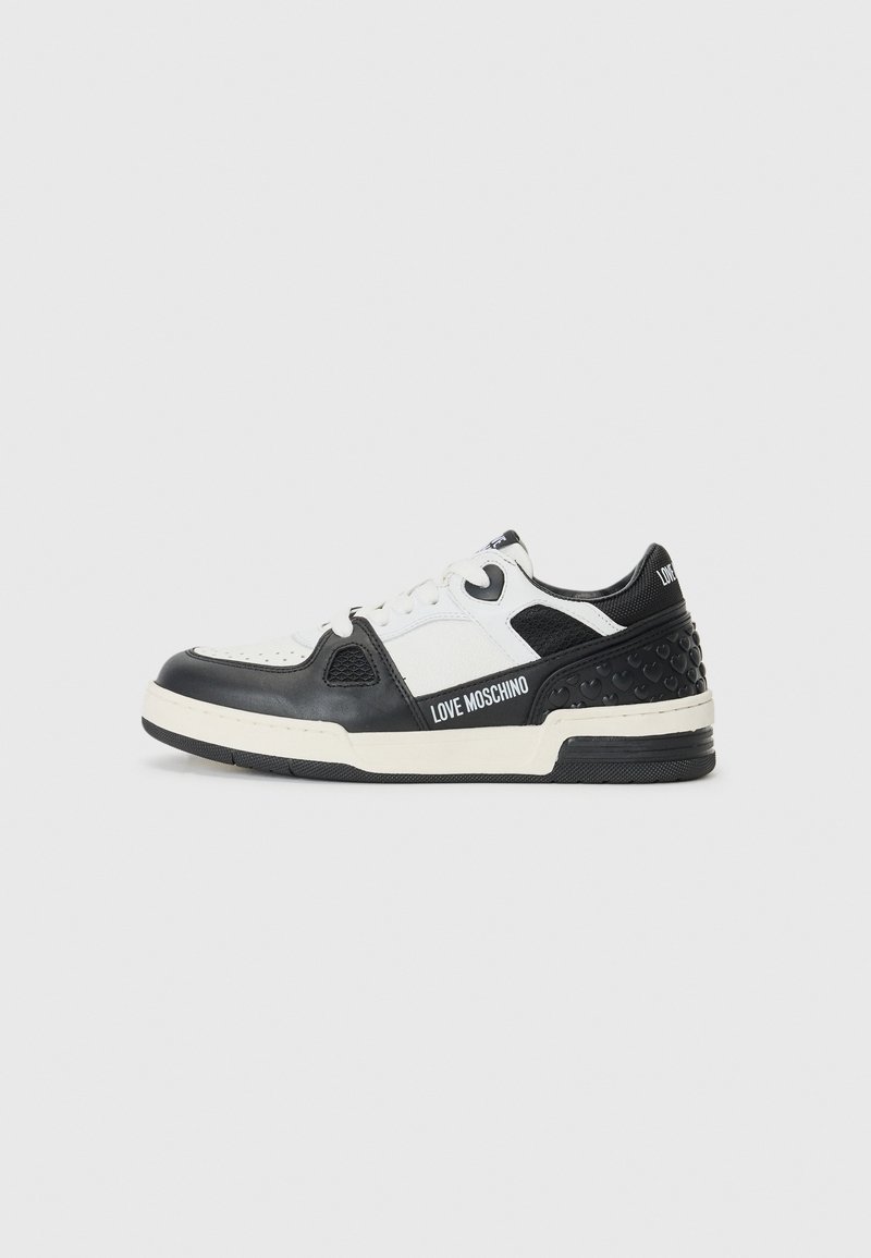 Zwart-witte sneaker met leren bovenwerk, geperforeerde details, textuur zijpaneel en contrasterende rubberen zool met branding.