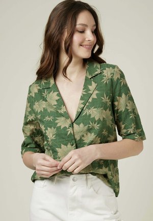 Chemise verte à manches courtes en tissu texturé, ornée d'un motif de feuilles dorées sur l'ensemble et dotée d'un col à revers avec des boutons.