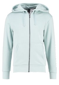 Sweat à capuche zippé bleu clair en tissu doux, doté d'une capuche, de deux poches avant et d'un logo imprimé en blanc sur la manche gauche.