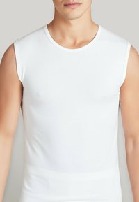 Canottiera bianca senza maniche in cotone con collo tondo. Tessuto liscio e forma aderente, che mette in risalto l'area del torso senza elementi di design aggiuntivi.