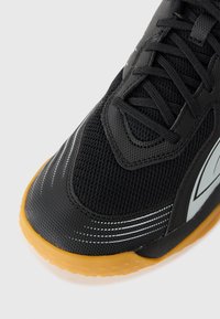 Sort atletisk sneakers med en åndbar mesh-overdel, gummisål, sølvfarvede detaljer og snøresystem. Har en rund tå og tekstureret greb.