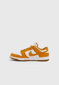 Teniska Nike Dunk Low v bílo-oranžovém provedení, s texturovaným kůžovým svrškem, děrovanou špičkou a gumovou podrážkou s kontrastním gumovým spodkem.