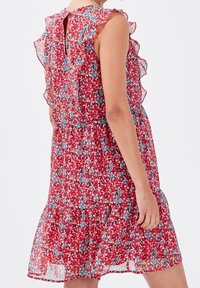 Red floral dress with a ruffled neckline and sleeves. Lightweight fabric, mid-length with a gathered waist, featuring a small back cutout.