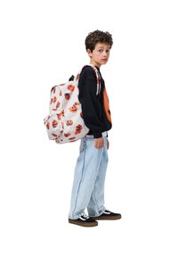 Biely batoh s oranžovými vzormi basketbalových loptičiek a usmievavých tvárí, s dvoma nastaviteľnými ramennými popruhmi a prednou vreckom na zips, ktorý nosí dieťa.