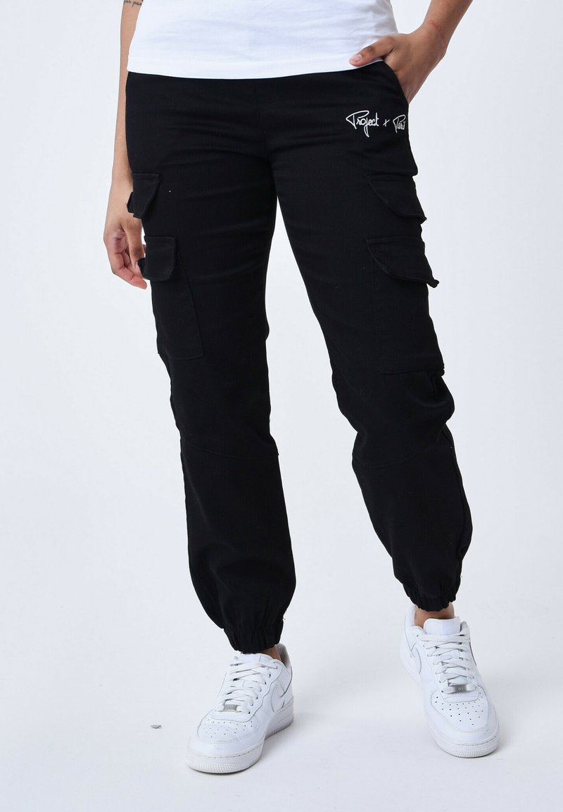 Pantaloni cargo neri con polsini elasticizzati e molteplici tasche laterali. Presenta un piccolo logo ricamato sull'anca. Realizzati in tessuto resistente.