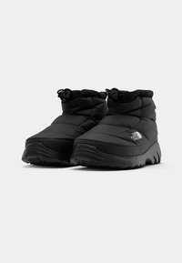 Juodi izoliuoti kulkšninių botai su tvirtais padangomis, reguliuojamais bungee laidais ir "The North Face" logotipu bootų išorinėje pusėje.