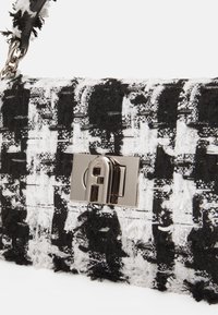 Černobílá kabelka z tvídu s texturovaným povrchem, vybavená kovovým zapínáním na klip a řetízkovým popruhem.