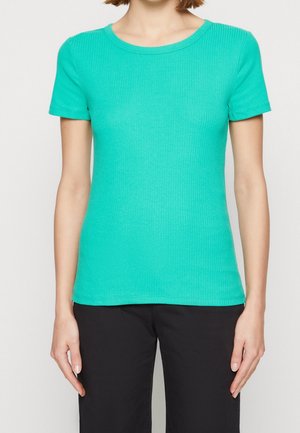 Ribbed, short-sleeve t-shirt in bright teal. Features a classic round neckline and a fitted design. Worn with black pants.