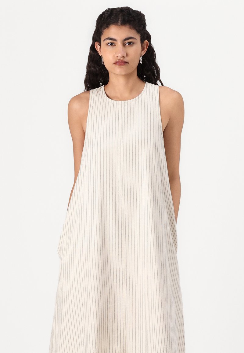 Ärmelloses cremefarbenes Kleid mit vertikalen Streifen, lockerer Passform, runder Ausschnitt und seitlichen Taschen, aus leichtem Stoff gefertigt.