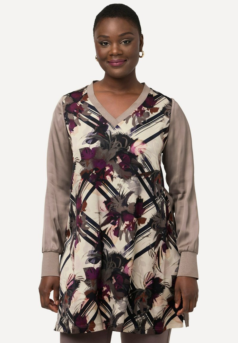 Sukienka w kwiatowy wzór o kremowym tle, z ciemnofioletowymi, różowymi i szarymi akcentami. Długie, gładkie beżowe rękawy oraz dekolt w kształcie litery V.
