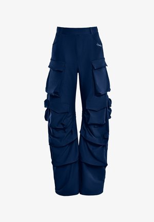 Navy zila cargo bikses no mīkstas auduma, ar vairākiem lieliem kabatām, brīvu piegriezumu un izteiksmīgu savilktu detaļu sānos.
