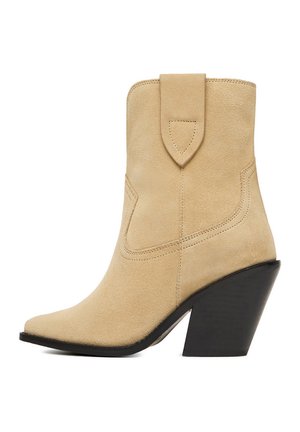 Stivaletto alla caviglia in suede beige con punta appuntita, cuciture decorative, linguetta per tirare e tacco alto nero spesso inclinato.