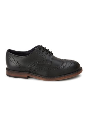 Sort læder brogue-sko med perforerede dekorative mønstre og brun sål, set fra siden på en hvid baggrund.