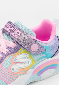 Zapatillas para niños de Skechers con parte superior de malla azul claro, tira purpurina morada y acentos multicolores. Cuenta con botón que se ilumina y suela de arcoíris.