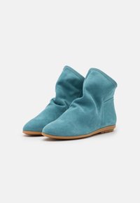 Suedes ankelsko i teal med en blød tekstur, der har et slouchy design og en fleksibel gummisil, der giver komfort og lethed i brug.