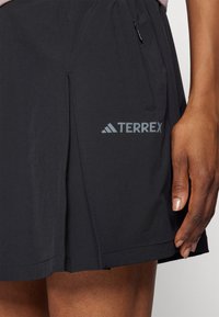 Černá sportovní sukně s jemně texturovanou tkaninou, se subtilním logem TERREX a bočním zipovým kapsou.