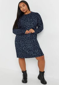 Robe à manches longues bleu marine avec un motif léopard, dotée d'une coupe décontractée et d'un col rond. Associée à des bottes chelsea noires à lacets.