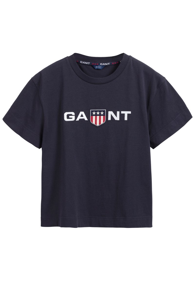 Tmavě modré bavlněné tričko, krátké rukávy, kulatý výstřih. Obsahuje bílé vyšívané logo "GANT" a design štítu se hvězdami a pruhy.