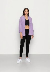 Lavendelfärgad kordfloddsoversized skjorta, svart crop top, svarta skinny jeans och vita sneakers. Rakt snitt med knäppning och långa ärmar.
