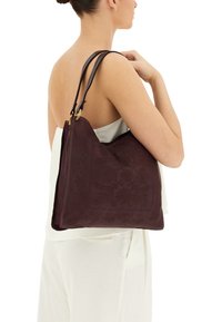 Borsa in pelle bordeaux con un motivo floreale testurizzato, dotata di due manici in pelle scura e un accento in metallo color oro.