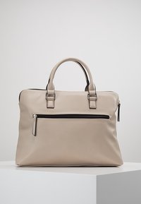 Beige synthetische Handtasche mit zwei Tragegriffen, einem Reißverschluss-Hauptfach und einer Fronttasche mit einem schwarzen Reißverschluss. Glatte Textur.