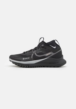 Zapatilla de trail running negra con parte superior texturizada, marca Gore-Tex, acentos reflectantes, mediopie amortiguado y suela resistente para tracción.