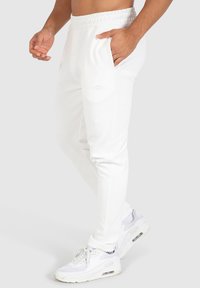 Witte joggerbroeken van zachte stof, met een elastische tailleband en zijzakken, gecombineerd met witte sportschoenen.