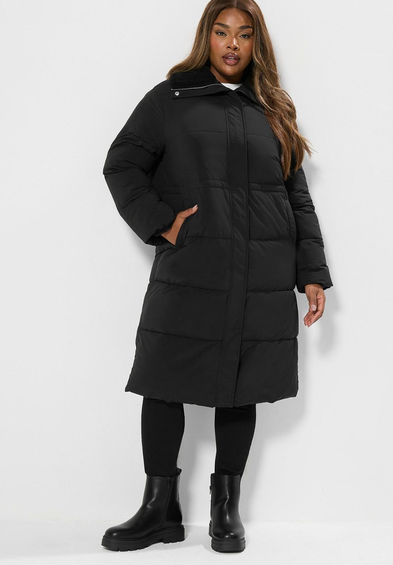 Czarna pikowana kurtka z wysokim kołnierzem. Posiada boczne kieszenie i zamek błyskawiczny, zestawiona z czarnymi botkami za kostkę.