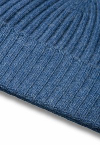 Berretto lavorato a maglia blu con texture a coste, che mette in evidenza un filato spesso e un sottile motivo melangiato. Il bordo curvo sottolinea la forma del cappello.
