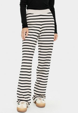 Pantalons rayés en beige et noir, dotés d'une large taille et d'une coupe décontractée. Le matériau semble doux avec une texture lisse.