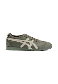 Green sneakers with a textured material, featuring light beige stripes and laces, a round toe, and a rubber outsole with a serrated pattern.