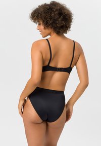 Schwarzes Dessous-Set mit einem BH mit verstellbaren Trägern und Häkchenverschluss, kombiniert mit hochgeschnittenen Slips, beide aus glattem Stoff.