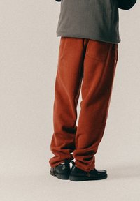 Kottide, roostes värvi pehmed dressipüksid, millel on elastne vöökoht, on kokku sobitatud mustade ankle'ite jalanikega, millel on tugev tald.