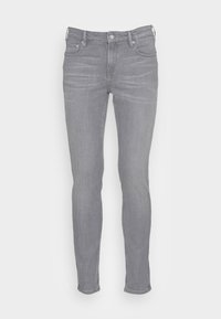 Vaqueros ajustados de mezclilla gris con diseño de cinco bolsillos, ligera decoloración, herrajes metálicos y cierre de cremallera. Sin logotipo de marca visible.