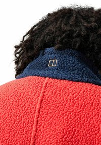 Fleecejack met een felrode stof met een gestructureerde afwerking, aangevuld met een donkerblauwe kraag en een klein geborduurd logo-detail.
