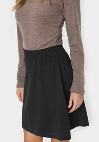 Jupe en jersey noire avec une large ceinture élastique, présentant un design évasé et un ourlet qui tombe au-dessus du genou. Texture lisse, style décontracté.