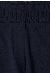 Gros plan sur la ceinture élastique bleu marine et le tissu supérieur d’un pantalon décontracté ou d’un jogging.