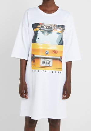 Hvid oversized t-shirt kjole med et grafisk motiv af en gul taxa, med "DKNY" logo og tekst nederst, lavet af blødt bomuldsmateriale.