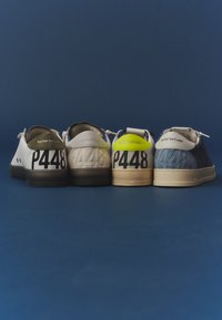 Quatre paires de baskets en blanc, beige, crème avec jaune et bleu, vues de dos avec le texte "P448" et "You Can Surf Later".