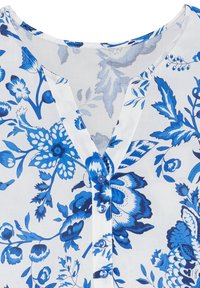 Květinová blůza z lehkého, průsvitného materiálu s modro-bílými vzory. Má výstřih do V a zapínání na knoflíky s modrými knoflíky.