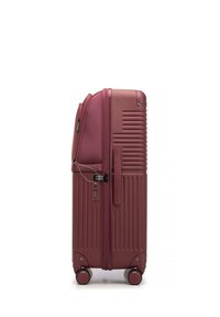 Valise rigide de couleur bordeaux profond, avec des rainures verticales, deux roulettes, un verrou par combinaison et une fermeture éclair pour plus de sécurité.