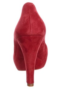 Scarpa con tacco alto in suede rosso, dal design affusolato, punta appuntita e tacco sottile. La texture è morbida e liscia, che mette in evidenza un profilo elegante.