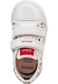 Sneaker bianco in velcro con etichetta rossa a contrasto, motivi grafici neri, punta arrotondata, superficie testurizzata e soletta imbottita.