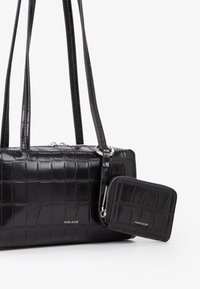 Borsa a tracolla nera in finta pelle di coccodrillo con due spallacci, hardware in argento e portafoglio coordinato attaccato con chiusura a zip e logo in rilievo.