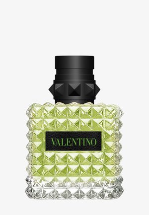 Botella cuadrada de perfume de vidrio con líquido verde, tapa negra adornada con tachuelas y etiqueta negra con texto verde "Valentino".