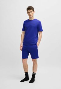 Blauw T-shirt met korte mouwen en bijpassende shorts, van gestructureerde stof, met zwarte logoaccenten. Draag het met zwarte crew-sokken met witte letters.