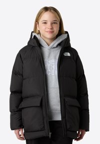 Chaqueta de plumas negra con capucha, que presenta un cierre de cremallera en la parte delantera, dos grandes bolsillos frontales y un logo en la parte superior izquierda. Llevada sobre un sudadera gris.