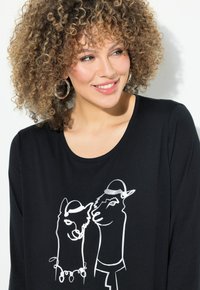 Schwarzes Langarmshirt mit einem weißen Grafikdruck von zwei Lamas, die Hüte tragen, mit glatter Textur und rundem Ausschnitt.